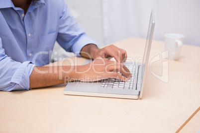 Mid section of businessman using laptop at desk