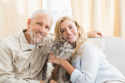 Happy couple with pet cat on sofa