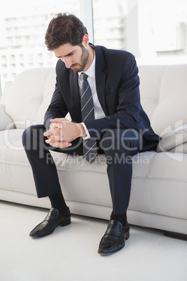 Nervous businessman sitting on couch