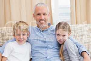 Father smiling at camera with his children on sofa