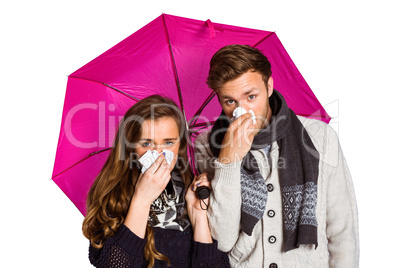 Couple blowing nose while holding umbrella