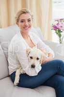 Happy blonde cuddling with puppy on sofa
