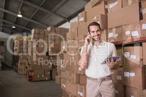 Worker with mobile phone and digital tablet in warehouse