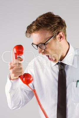 Angry geeky businessman holding telephone