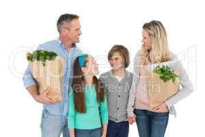 Smiling family standing holding bag of healthy groceries