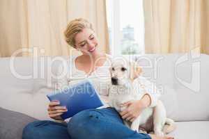 Happy blonde using tablet pc with puppy