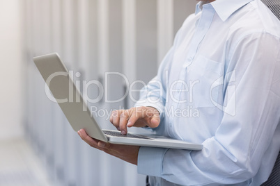 Mid section of a technician typing on his notebook