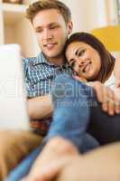 Happy young couple relaxing on the couch with laptop