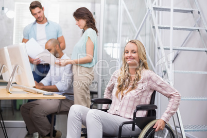 Woman in wheelchair smiling at camera with team behind her