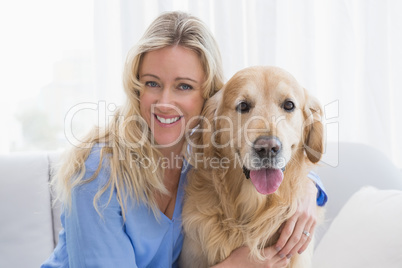 Smiling blonde woman hugging her golden retriever
