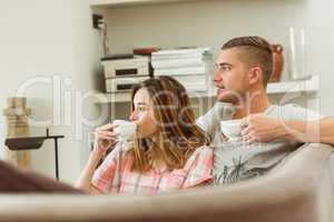 Cute couple relaxing on couch with coffee