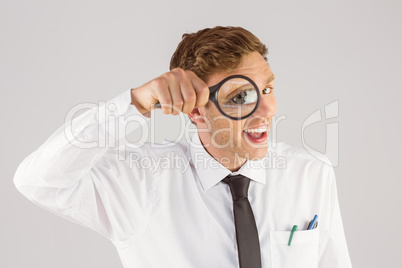 Geeky businessman looking through magnifying glass