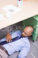 Businessman sleeping under desk
