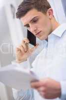 Young technician calling and reading a document