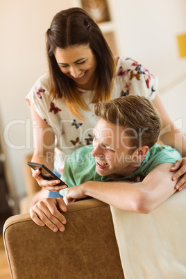 Cute couple looking at smartphone on couch