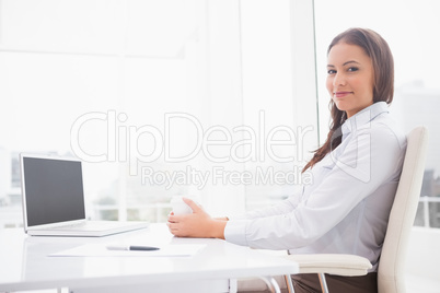 Happy businesswoman having coffee at her desk
