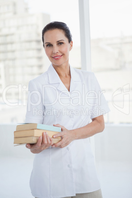 Smiling doctor holding medical books