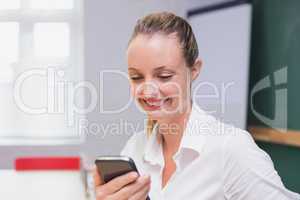 Blonde smiling businesswoman using smartphone
