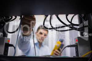 Technician using cable tester while fixing server