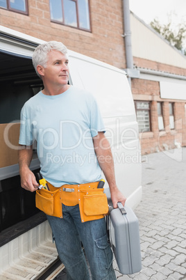 Man with tool belt and briefcase by van