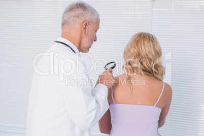 Doctor examining patient with magnifying glass