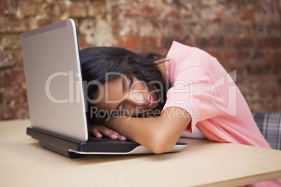 Casual businesswoman sleeping at her desk on her laptop