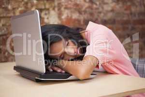 Casual businesswoman sleeping at her desk on her laptop