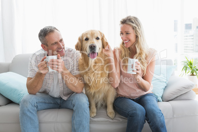 Smiling casual couple sitting on couch having coffee