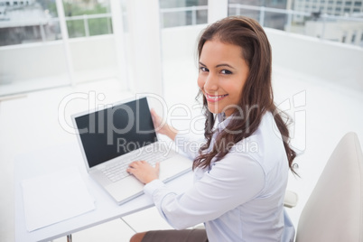 Smiling businesswoman using laptop at her desk