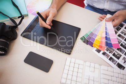 Designer using graphics tablet and colour charts