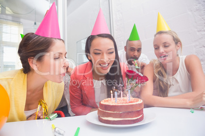 Businesswoman blowing the candles on her birthday cake