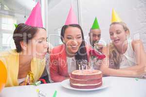 Businesswoman blowing the candles on her birthday cake