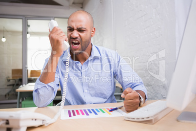 Angry businessman using telephone at desk