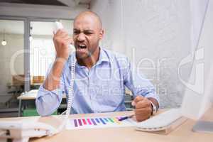 Angry businessman using telephone at desk