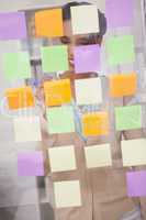 Smiling businesswoman writing on sticky notes on window