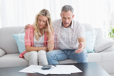 Worried couple calculating bills on the couch