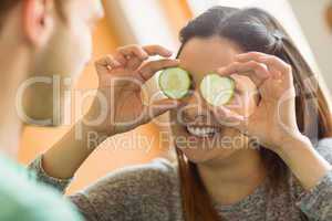 Cute brunette holding cucumber slices over eyes