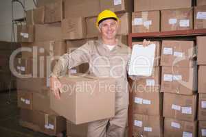Delivery man with box and clipboard in warehouse
