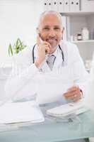 Smiling doctor phoning and using computer