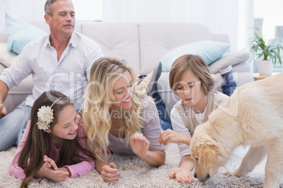 Smiling family with their pet yellow labrador on the rug