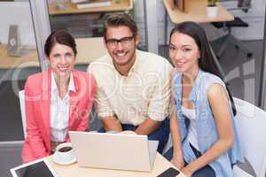Smiling business team using laptop and having coffee