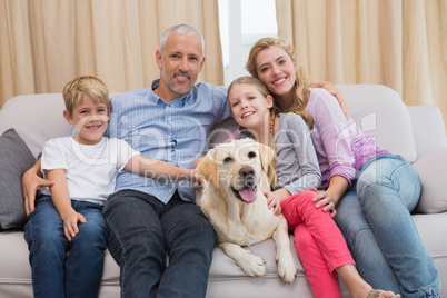 Parents and their children on sofa with labrador