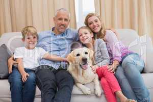 Parents and their children on sofa with labrador