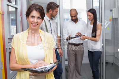 Casual businesswoman holding her diary smiling at camera