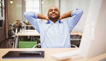 Relaxed businessman listening music at desk