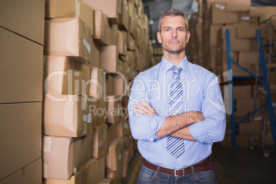 Serious manager with arms crossed in warehouse