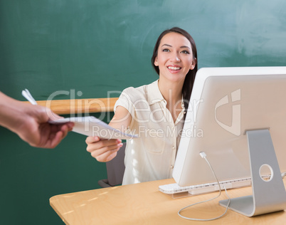 Hand giving document to businesswoman at desk