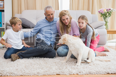 Happy parents and their children on floor with puppy