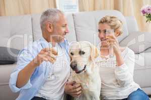 Happy couple with their pet dog drinking champagne