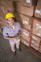 Worker with clipboard in warehouse